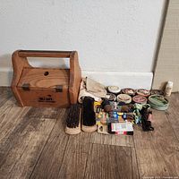 Full lot showing wooden box labeled Kiwi Shoe Groomer and various shoe care items including brushes, tins of polish, cloths, laces, and applicators.