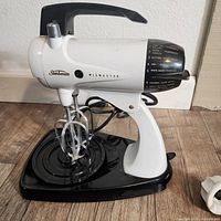 Front view of white Sunbeam Mixmaster Plus stand mixer on black base with double beaters attached