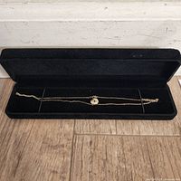 Yellow gold plated necklace in a black velvet box showing full length of chain and pendant.