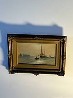 Framed watercolour painting showing sailboats on water, mounted in an ornate gold frame with artist name plaque.