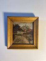 Framed village scene artwork with a prominent gold-tone frame, showing overall condition and size.