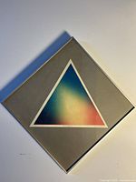 Full view of framed lithograph showing triangular gradient print, grey mat, and silver frame