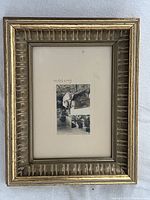 Front view of the framed artwork showing the painting, matting, signature, and gold-toned decorative frame.