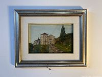 Framed signed oil landscape painting depicting a building with a cypress tree on a hill