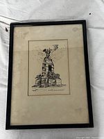 Framed full view of the sketch showing the monument with matting and black frame, mounted on a white cloth background.
