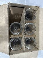 Top view of six clear glass flutes packed in cardboard box with dividers.