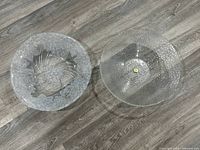 Two clear textured glass decorative bowls seen from above placed on wooden floor