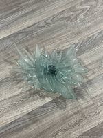 Top-down view of the tinted abstract glass sculpture showing its swirling jagged design and tinted green glass material.