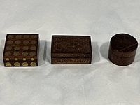Three wooden jewelry boxes with brass inlay displayed closed, showing ornate floral and geometric patterns on tops and sides.