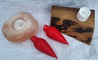 Pink rock salt candle holder with opening holding a tealight candle, sculpted wood candle holder with a white flameless LED candle and two red wax candles