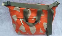 Orange and beige patterned overnight bag with olive green carrying handles and an adjustable shoulder strap shown from the outside.