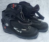 Pair of Rossignol black backcountry ski boots showing side view with brand and model details, zipper and Velcro strap.