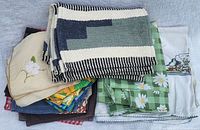 Lot of folded woven placemats and various cloth napkins layered showing patterns and embroidery.