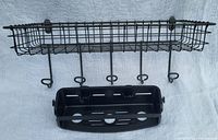 Black metal wire wall-mounted shelf with five hooks and a black plastic suction cup basket attached underneath.