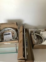 Several boxed bathroom accessories including curved towel rings, a metal towel bar, and a glass shelf.