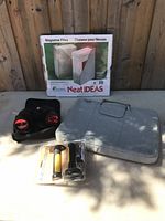 Binoculars, laptop case, magazine file box, and bike handle grips on table with wooden fence backdrop.