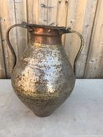 Full view of the large bulbous copper vase showing hammered texture, patina, and two curved handles.