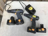 Two electric drills displayed with their battery packs and charger on a white surface. McCulloch corded drill and Johnson cordless drill visible.