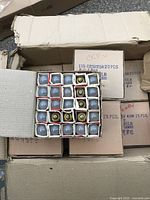 Top view of one box open showing light bulbs arranged in a grid, bulbs have metallic screw bases and frosted glass tops.