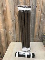 Four brown metal legs bundled together with tape, standing upright on a table against a wooden background.