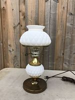 Full view of the milk glass electric table lamp from the front with visible cord and brass base shown.