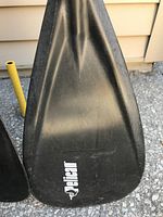 Close-up of broad black paddle blade with Pelican logo.