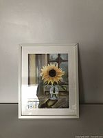 Framed acrylic painting with a sunflower in a glass jar, signed, showing full front view in a white frame.