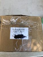 Close-up photo of the label on the box showing screw details and quantity, with one screw taped on top of the box for reference.