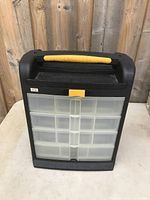 Single black and yellow storage organizer with 15 clear drawers on table in front of wood panel background.