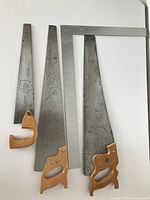 Three vintage hand saws arranged vertically with ruler to show size. Small is 15.5 inches, middle is 23.5 inches, large is 24 inches.