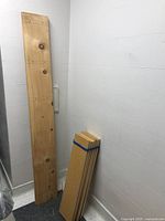 Tall wooden plank leaning against the wall, showing natural wood grain and knots.