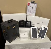 Photo of all boxes arranged on a table including Beats headphones box, iPhone boxes, EarPods box, and cases.