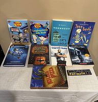 Overview of various books including children's joke books, fiction, and anatomy educational books arranged on table.