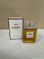 Chanel N°5 Paris Eau de Parfum bottle displayed next to its original box on a white cloth background.