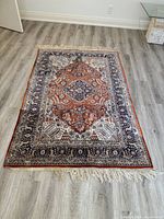 Full view of rug laid flat showing overall pattern, border and fringe