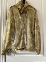 Front view of Michael Kors rain jacket showing zipper, hood, and front pockets with leaf pattern.