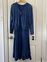 Full view of the blue lace dress and matching top hanging on a door, showing the overall style and color.