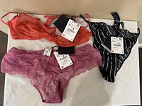 Photo showing three Zara undergarments new with tags: orange lace brassiere, purple lace panty, and black and white striped panty.