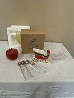 Overview of the sleigh appetizer dish, packaging box, styrofoam insert, four appetizer forks with holiday ball tops, and an apple for size reference.