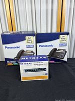 Two Panasonic KX-TS4200B telephone system boxes and one Netgear 8-port gigabit desktop switch box displayed together