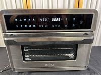 Front view of Aria ATO-898 digital air fryer oven showing control panel with LED touchscreen and cooking presets, and oven door with window and handle.
