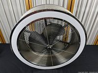 Top front view of the round ceiling fan showing chrome circular grille and black blades inside.