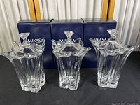 Three clear crystal Mikasa Floral collector's jar vases displayed in front of their original Mikasa blue boxes, showing multi-faceted floral design and petal-like rims with knob handles.