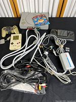 The full bundle spread out showing all consoles, controller, cables and accessories grouped on a black surface against a wooden backdrop.