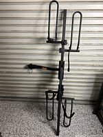 Full view of the black metal Swagman XTC2 hitch-mounted bike rack in stored position showing frame, wheel hoops, and mounting arm