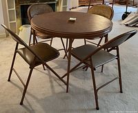 Round card table set up with four folding chairs, showing table and front view of chairs.
