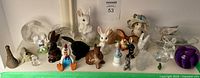 Group photo of 28 decorative figurines including various bunny and other animal designs in ceramic, glass, and resin materials.