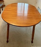 Rectangular wood dining table surface and turned legs, showing polished wood grain and rounded edges