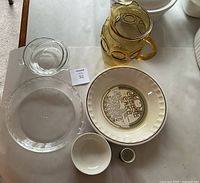 Top-down view of the 7-piece lot arranged on a table including pie plates, pitcher, egg cup, small bowl, glass lid, and metal cup.