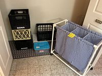Photo showing the divided laundry hamper, four milk crates stacked in various configurations, and a small blue plastic storage bin on the floor.